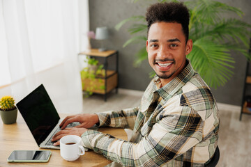 Wall Mural - Side view young smart IT man wearing casual clothes hold use work on blank screen laptop pc computer chat online sitting at table in coffee shop cafe relax rest in restaurant during free time indoors.