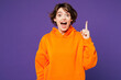 © ViDi Studio - Young proactive shocked smart happy Caucasian woman wear orange hoody casual clothes holding index finger up with great new idea isolated on plain purple background studio portrait. Lifestyle concept.