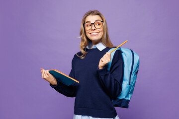 Poster - Young girl student in blue casual clothes glasses backpack bag write down in exercise book notebook diary notes point aside isolated on plain purple background High school university college concept