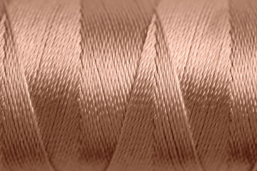 Wall Mural - Sewing thread in mocha mousse shade, closeup. Trendy color of 2025 year