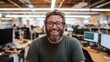 © SimpleDesignStudio - A Joyful Male Employee Smiling in a Modern Office Environment Surrounded by Computer Monitors and Workstations, Showcasing a Collaborative Workplace Culture