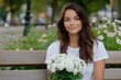 © Milos - A young woman sits with a warm expression while holding a bouquet of flowers, her relaxed demeanor radiating peace and a joyful connection to the world around her.