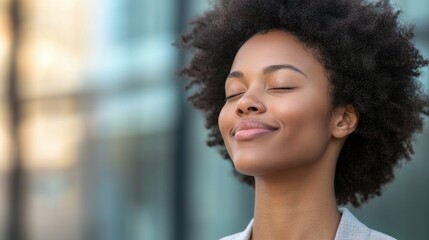 Wall Mural - Smiling young woman with natural curly hair enjoying a moment of peace outdoors with eyes closed against a blurred urban background Copy Space