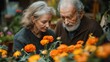 © sompoch - An elderly couple admires vibrant orange flowers, showcasing a moment of connection and appreciation in a lush, floral setting.