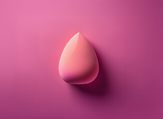 Leinwandbilder - A single, light coral-pink teardrop-shaped makeup sponge rests on a deeper pink background.  The image is clean, minimalist, and focuses on the object's form and color.