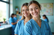 © photobuay - Two smiling female healthcare professionals in blue scrubs stand in bright medical setting, exuding positivity and teamwork