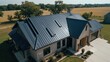 © The 2R Artificiality - Skilled metal roofing mechanics examining blueprint instructions for steel material sizing on modern home with black metal roof against open field backdrop.
