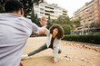 © Jordi Salas - A fitness trainer motivates his client by high fiving during an outdoor exercise routine, fostering encouragement and teamwork in fitness activities.