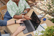 © Seventyfour - Top view of unrecognizable African American female landscape architect pointing at laptop screen discussing public space design with colleague, while man keeping fingers on touchpad at table outdoors