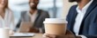 © Thee - A business meeting setting where a person holds a coffee cup, suggesting a casual yet professional atmosphere among colleagues.