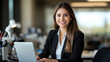 © Tondone - A confident professional woman smiles while working on her laptop in a modern office