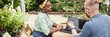 © Seventyfour - Website header shot of smiling female landscape architect of Black ethnicity sitting at table with male colleague discussing garden project, choosing shrubs and trees in plant nursery