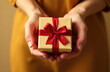 © Alena - Woman's hands holding craft paper gift box with a present for Christmas, new year, valentine day or anniversary on golden background, top view