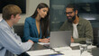 © Yuliia - Business people three colleagues smile team coworkers professional businesswoman businessmen company teamwork at table analyzing talking Indian Caucasian men woman project laptop at corporate office