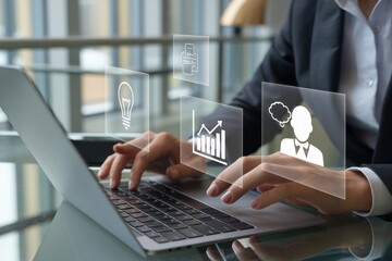 Businessperson working on laptop with holographic interface showing business analytics, ideas, and workflow.