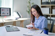 © Wasana - A woman is sitting at a desk with a laptop and a notebook