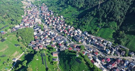 Wall Mural - Aerial shot of countryside village in the mountains with houses and green trees at day