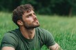 © MyJuly - Man with short hair and a beard is sitting in a field of grass. He is looking up at the sky