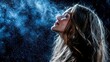 © MP_Artworks - A woman with long, flowing hair gazes upwards, surrounded by sparkles of perfume mist. Her face is softly illuminated by cool blue light against a dramatic dark background, creating an enchanting atmo