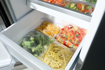 Wall Mural - Plastic bags with different frozen vegetables in refrigerator