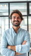 © Creative Vision - Confident young man smiling with arms crossed in a casual office setting.