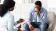© Prostock-studio - Depressed black guy crying at psychotherapist's office, seeking professional help at clinic. Professional psychologist having counseling session with unhappy male patient