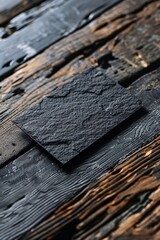 Poster - Black stone square resting on a wooden surface with a blurred backdrop