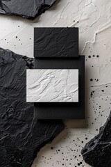 Aufkleber - Black and white business cards with a textured surface lying on black stones over a white background with black splashes