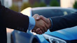 © ChimE - Two men seal a deal with a firm handshake at a car center, with a shiny automobile on display behind them.