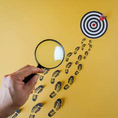 Fototapete - Achieve Your Business Goals: Magnifying Success. Hand holding magnifying glass focuses on target, symbolizing growth, investment, determination, and strategic  