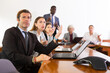 © JackF - Nervous man in suit sitting at desk with group of coleagues during meeting.