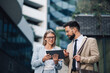 © Zamrznuti tonovi - Business people having informal meeting using digital tablet outside office building