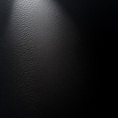 dark textured surface illuminated by a spotlight, creating a dramatic light and shadow effect.