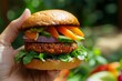 © Jumroon - Fresh and Colorful Vegetable Burger in a Hand with Greenery Background