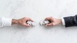 © BROPRADANA - Two hands connect puzzle pieces; collaboration, teamwork, on marble table.  Business solution concept