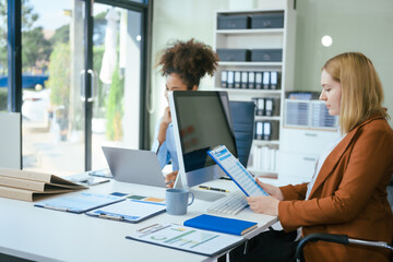 Wall Mural - An African American businesswoman and a Caucasian woman work at analyzing market data, developing business strategies,discussing financial growth while using a laptop spreading money for investment