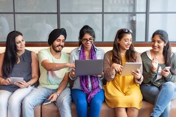 Wall Mural - group of diverse business people sitting together, using devices. smiling and engaged. business men 