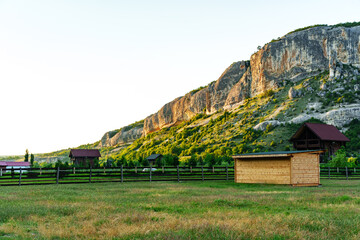 Wall Mural - sunset over a tranquil rural landscape with mountains and wooden structures in the foreground