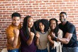 © Rawpixel.com - Group of five people smiling and posing with fists raised in front of a brick wall. They appear happy and united, showcasing a sense of camaraderie and strength. Successful team of diverse people.