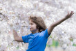 © Volodymyr - Spring free. Carefree kid with raised hands meditating, feeling calm near cherry blossom tree. Kid relaxed on spring nature. Kid closed eyes and feeds energy of nature, dreams.