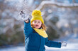 © Volodymyr - Kid playing with Snowball snow during snowfall. Snowball fight. Kid in a warm clothes, hat, hand gloves and scarf playing Snowball. Snowy winter day for kids. Child snowball fight in snow.