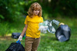 © Volodymyr - Kid in rubber gloves with trash bag clean up garbage on forest outdoor. Eco, environment conservation. Recycle pollution. Kid boy collecting garbage and plastic trash. Save environment. Eco kids.