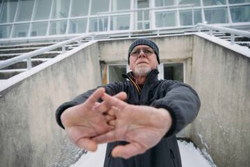 Wall Mural - Senior Man Performing Outdoor Stretching Exercises on Snowy Steps in Winter