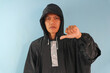 © Lailar Studio - Asian man wearing a raincoat while raising his thumbs down