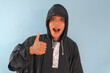 © Lailar Studio - Asian man wearing a raincoat raising his thumbs up