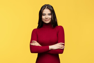 Wall Mural - Beautiful young woman in red dress is posing on yellow background.