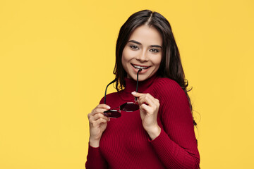 Wall Mural - Pretty young lady in red dress and sun glasses is posing on yellow background.