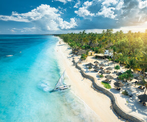 Wall Mural - aerial view of the sailboat on blue sea, empty white sandy beach, umbrellas at sunset. summer in zan