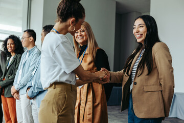 Wall Mural - diverse group of professionals networking and shaking hands at a business meeting