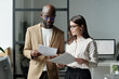 © TrueFrame Collective - Young serious businessman and brunette woman looking through financial documents while discussing papers